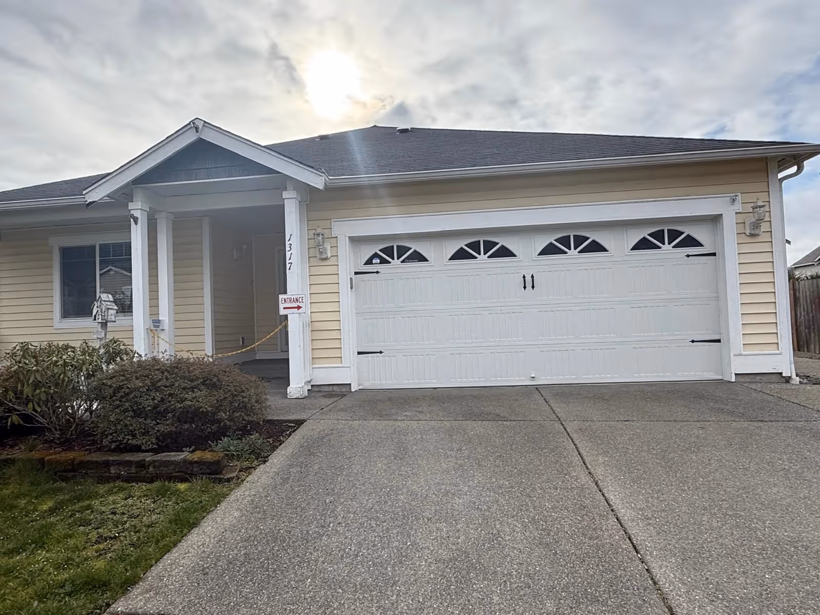 Front view of a beige, single-story house with a two-car garage and covered entrance.