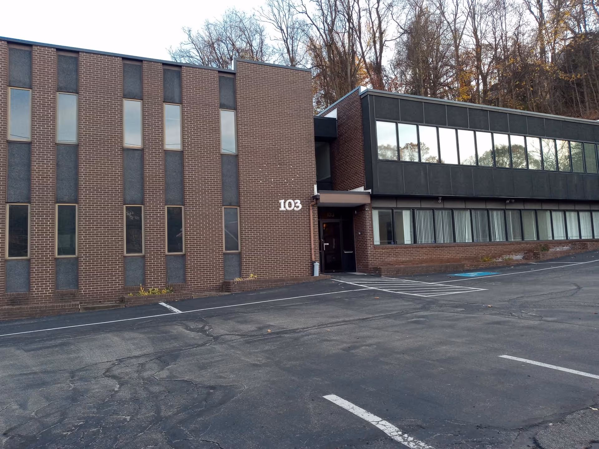 Exterior view of a brick facility with large windows and a parking lot