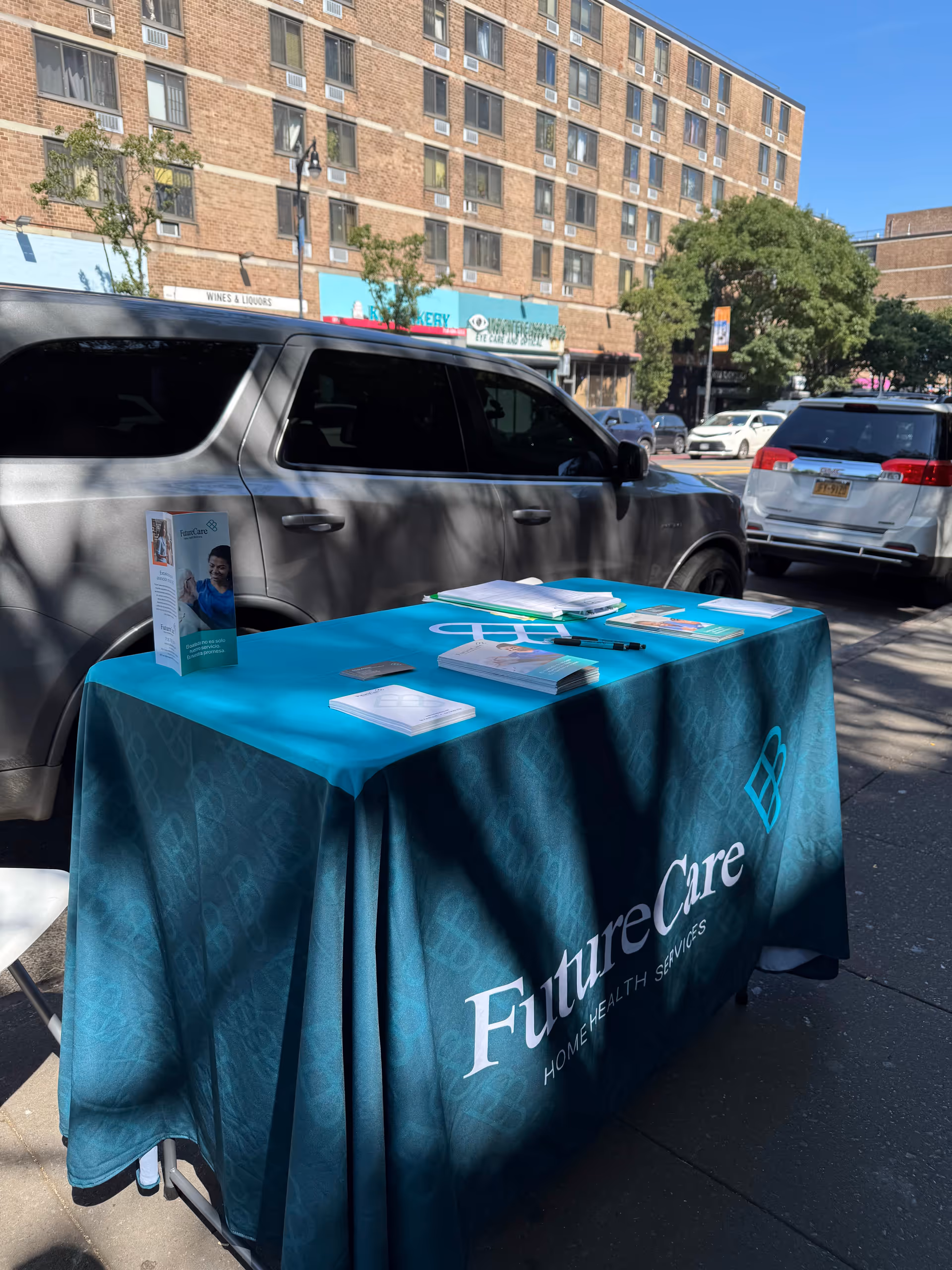Outdoor street-side table with teal FutureCare tablecloth and promotional brochures.