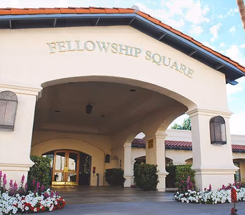 The Fellowship Square Mesa building entrance with arches and blooming flower beds.