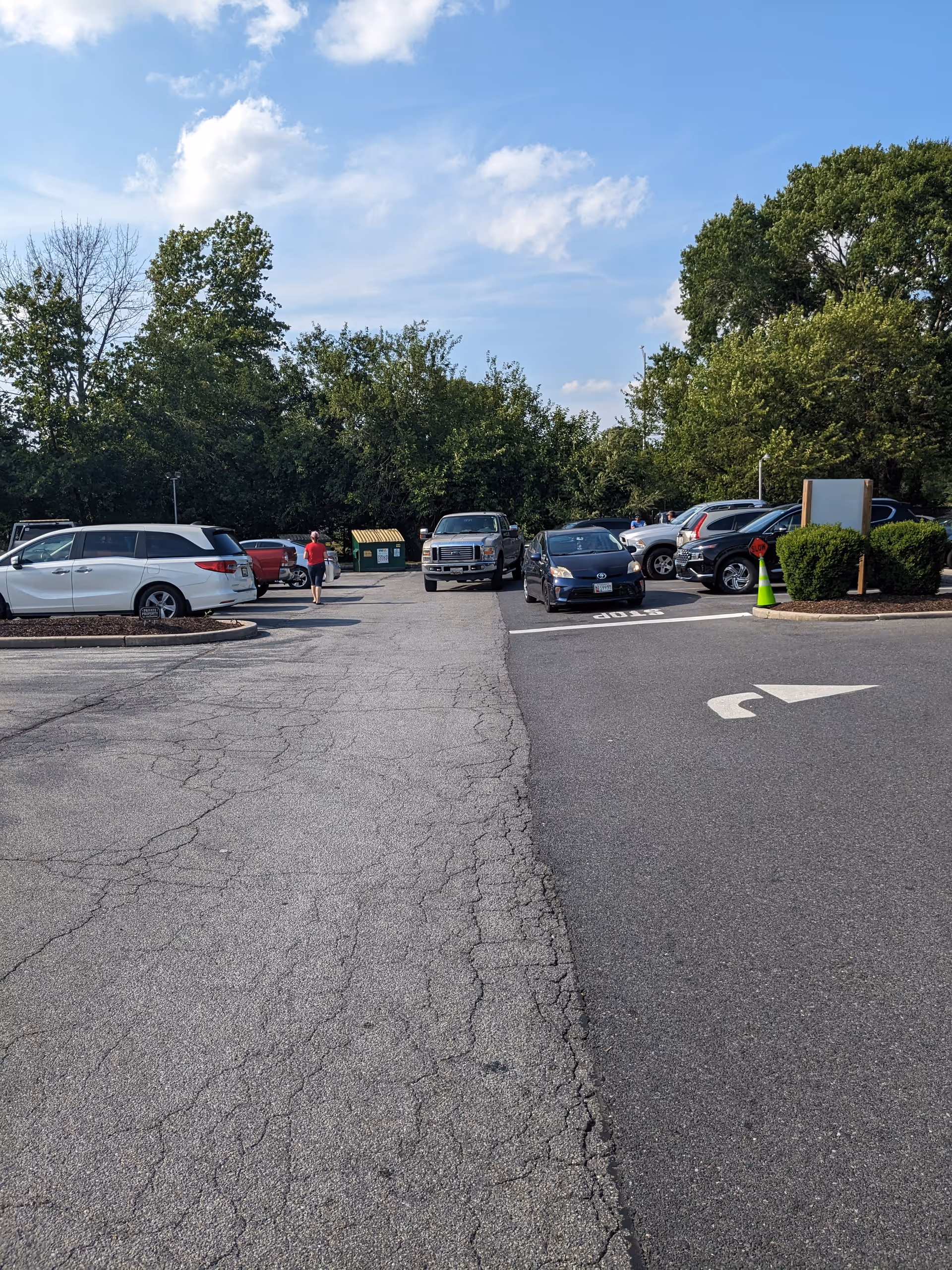 A parking lot outside a senior facility with multiple cars and green trees in the background.