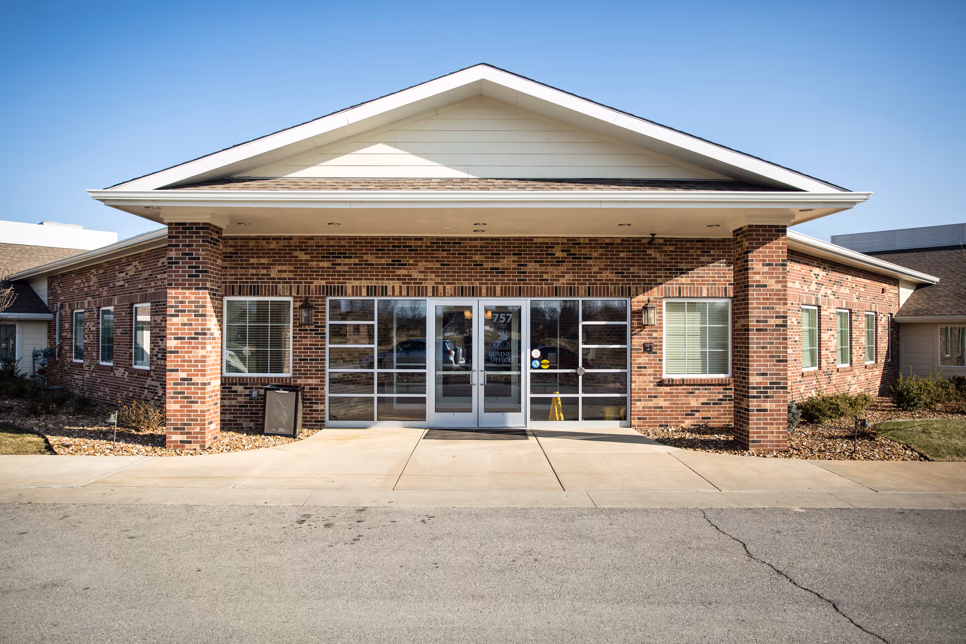 Brick senior living facility exterior with glass doors and a covered entrance.