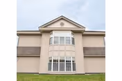 Front exterior of a beige multi-story nursing center with a prominent central bay window.