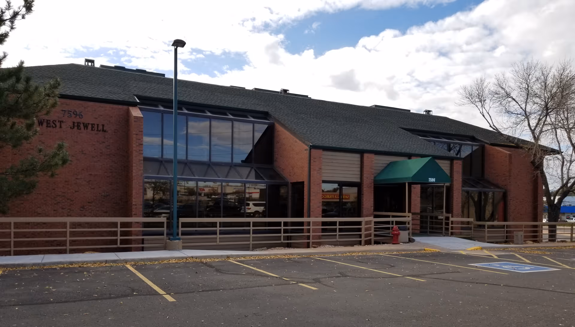 Brick senior living facility exterior with a glass front entrance and ramp.