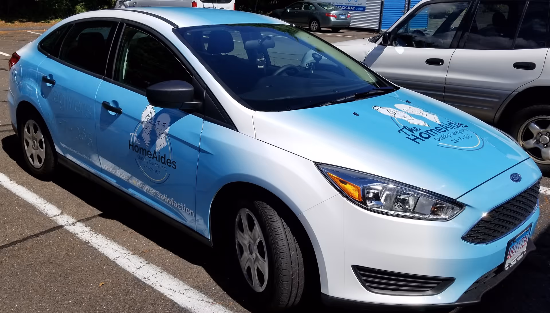 Blue and white caregiver service car parked in a lot.