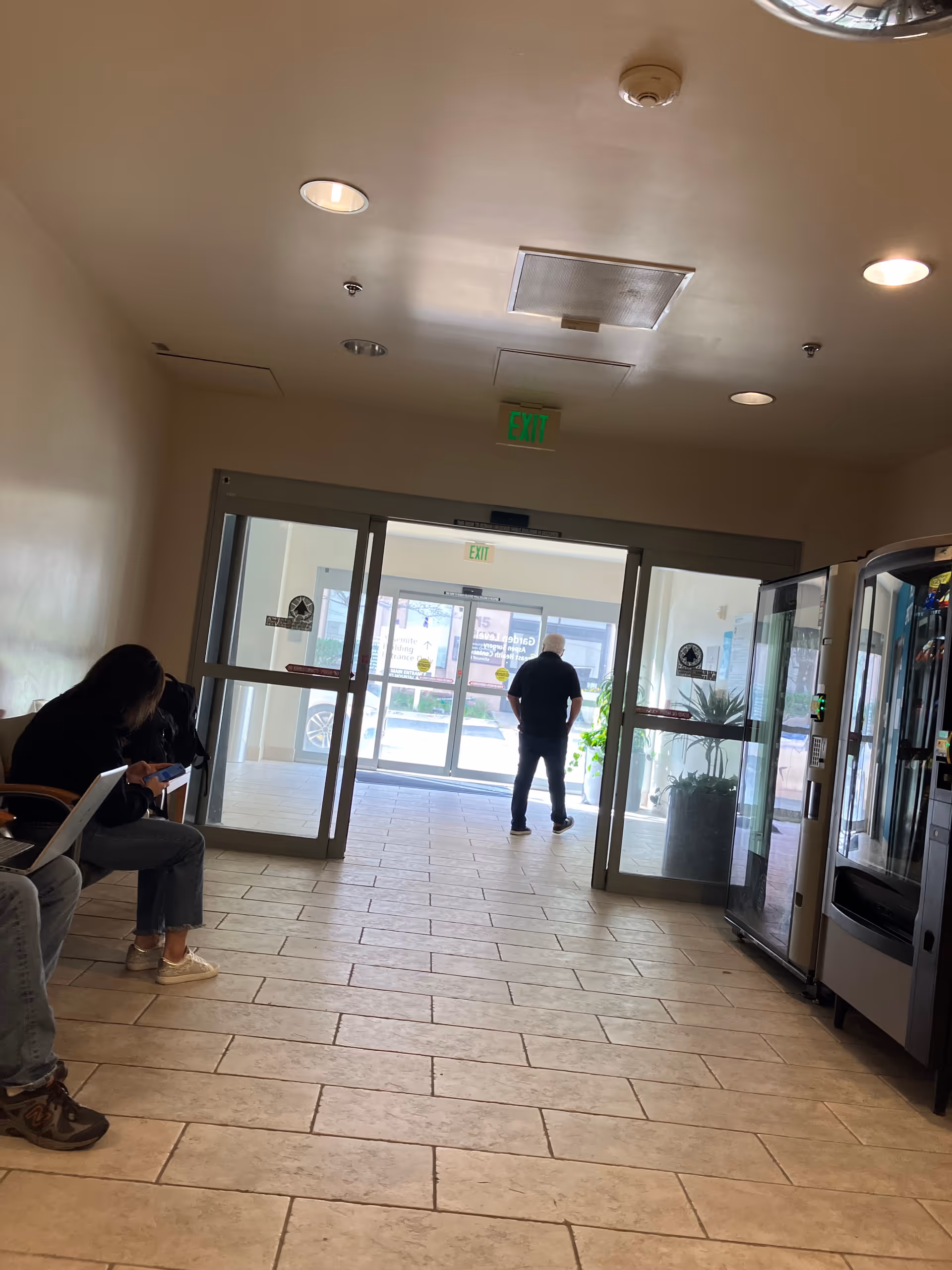 Lobby area inside Aspen Surgery Center with glass entry doors, seating, and a vending machine.