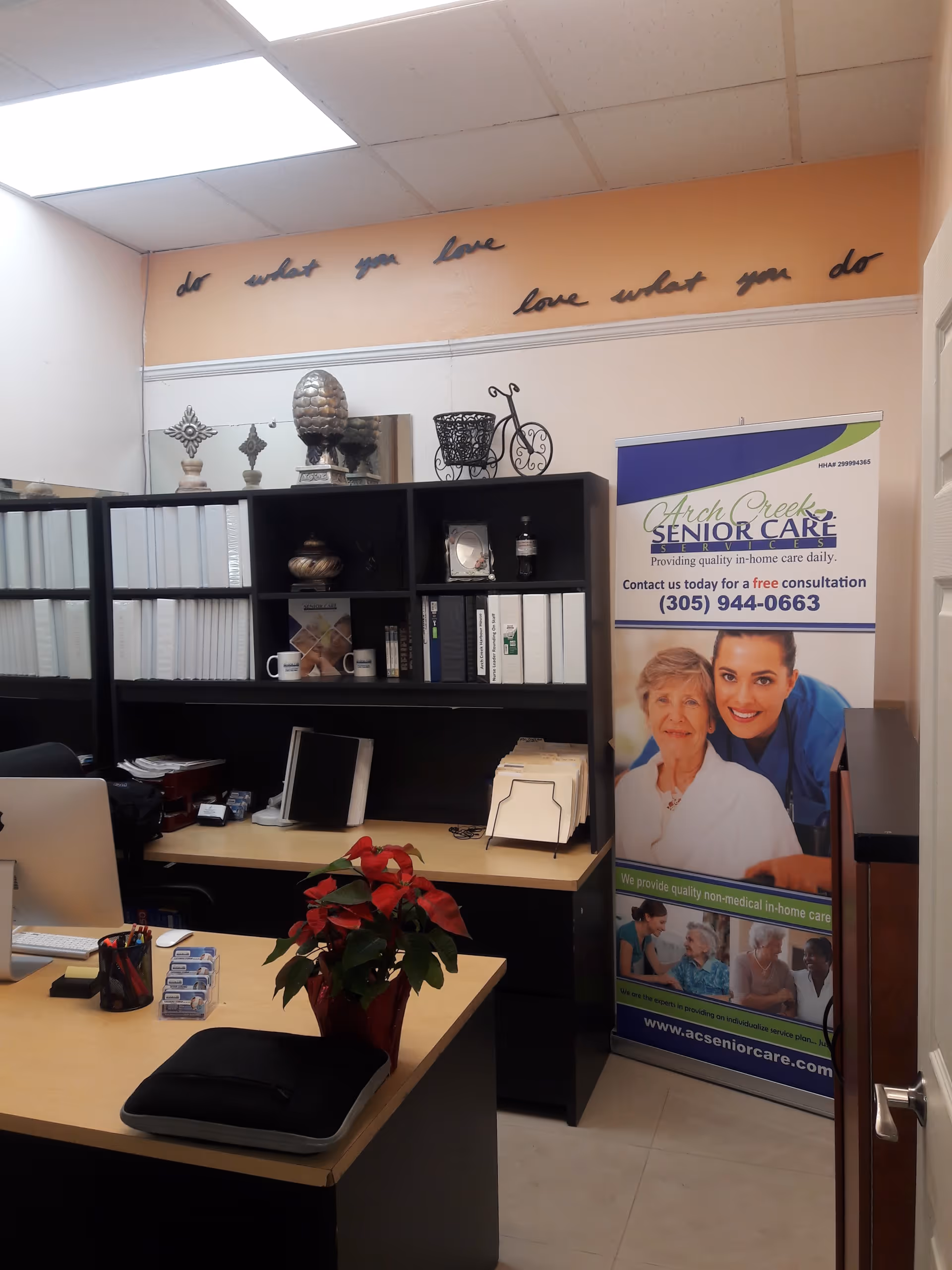 Office reception area featuring a desk, shelving, computer, poinsettia, and Arch Creek banner.