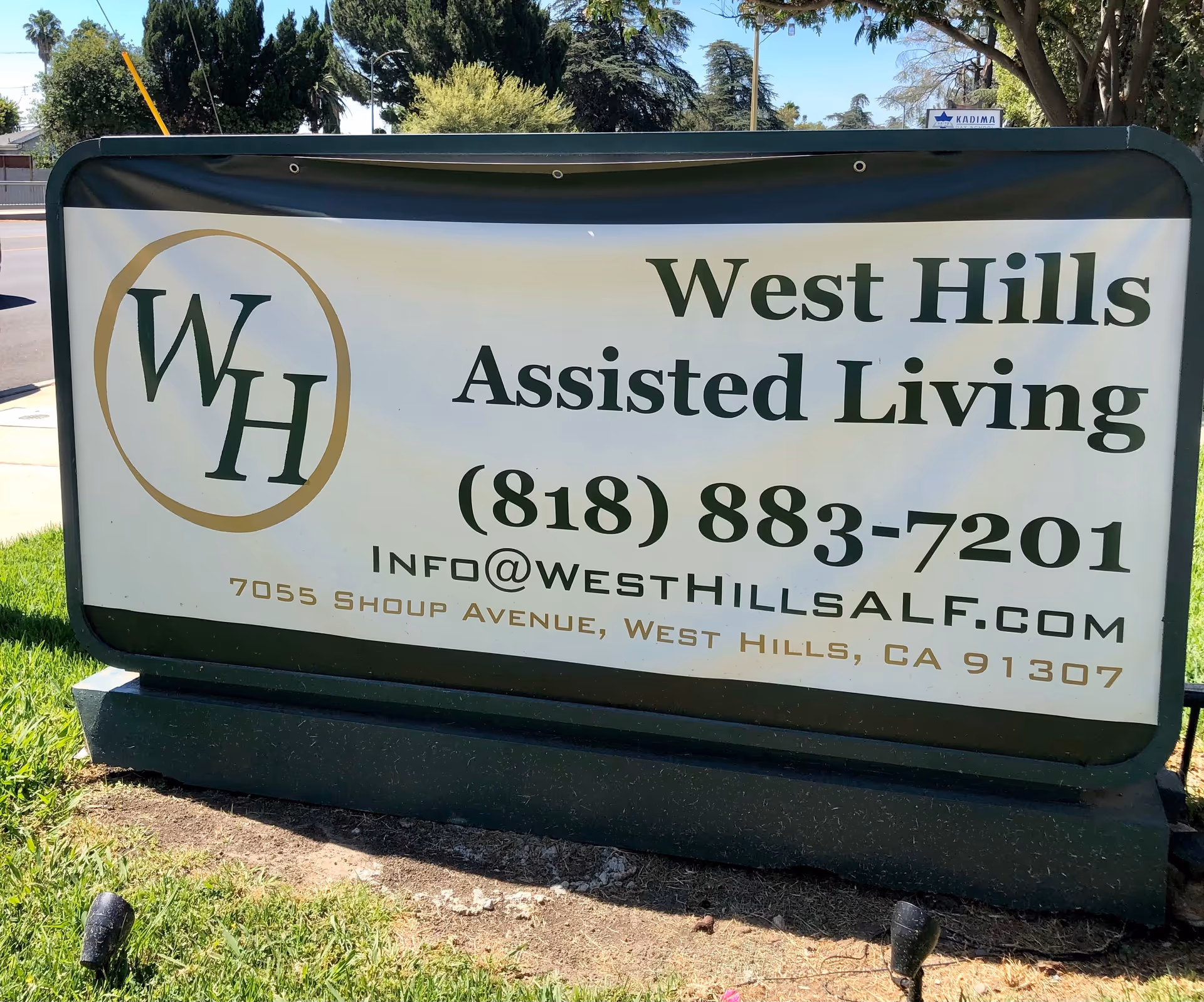 Outdoor sign for West Hills Assisted Living, featuring a logo, phone number, and address.
