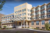Exterior view of a multi-story Willow Gardens Memory Care building with a glass entrance.