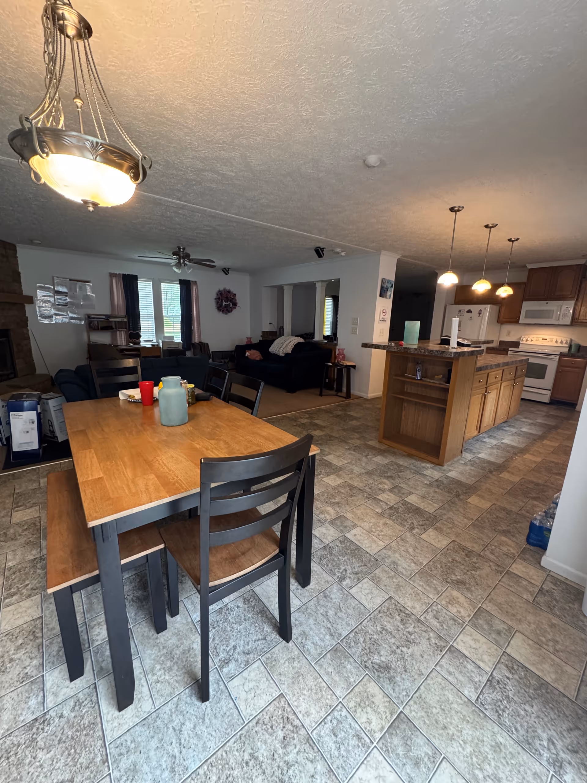 Open dining area with a wooden table, chairs, and a kitchen island in the background.