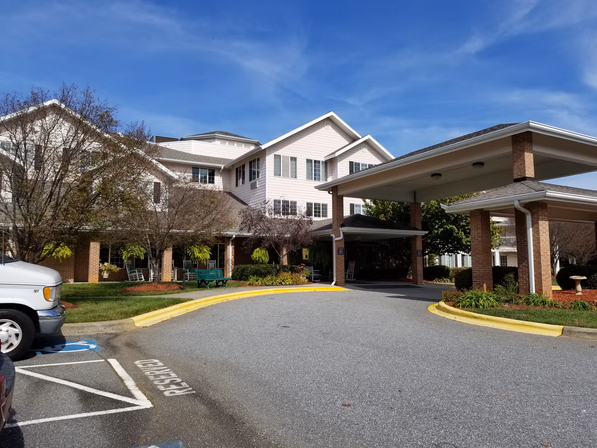 Creekside Terrace senior living building with covered entrance, parked vehicles, and landscaped grounds.