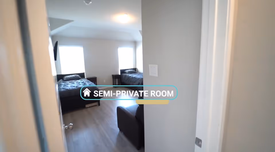 Two beds in a bright, semi-private bedroom with a small couch adjacent.