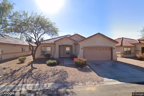 Front exterior view of a single-story assisted living home with a two-car garage and desert landscaping.