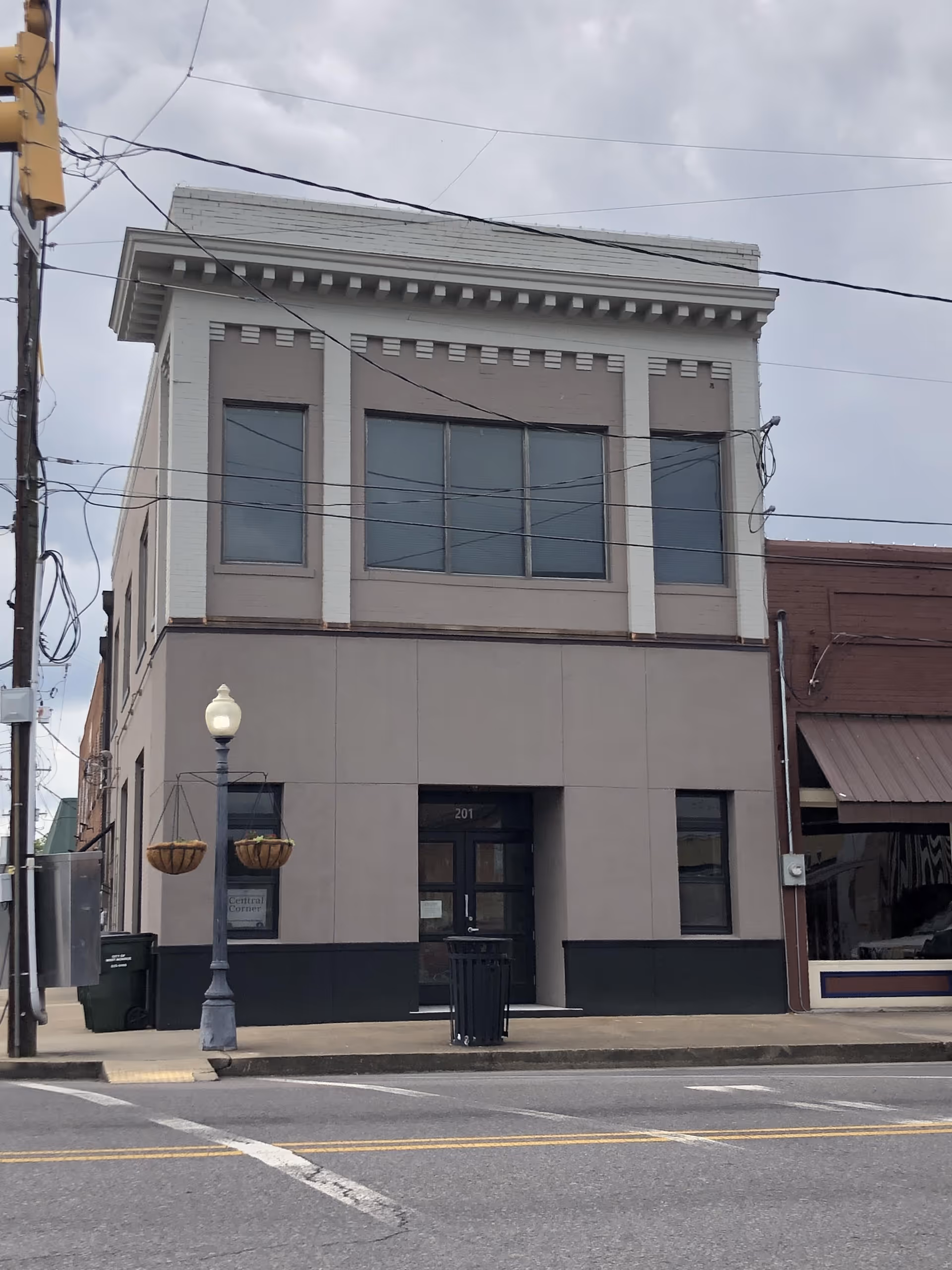 Two-story beige and gray building on a street with a central glass entrance.