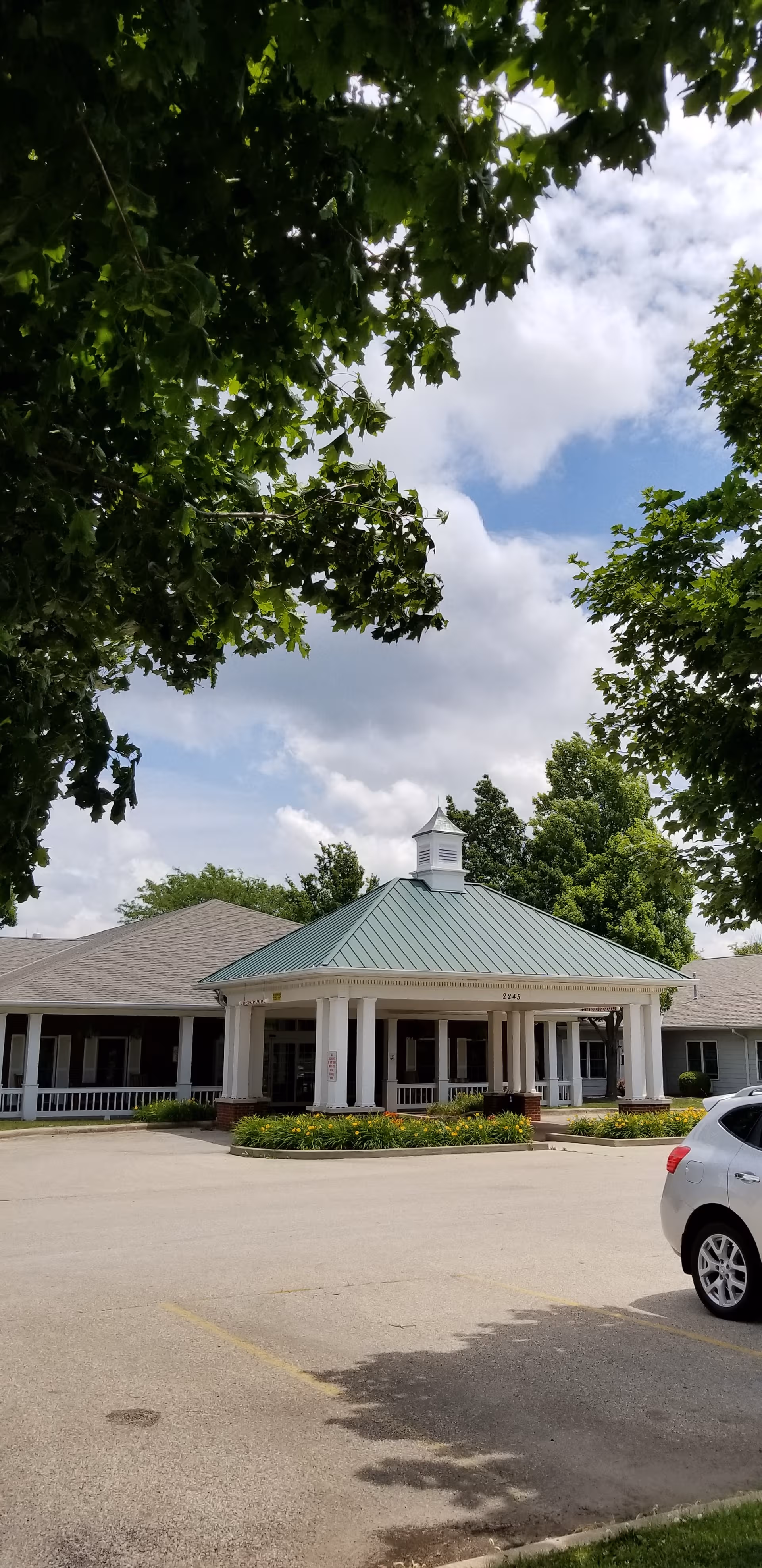 Hawthorne Inn senior living facility entrance with porte-cochère, green roof, and trees.