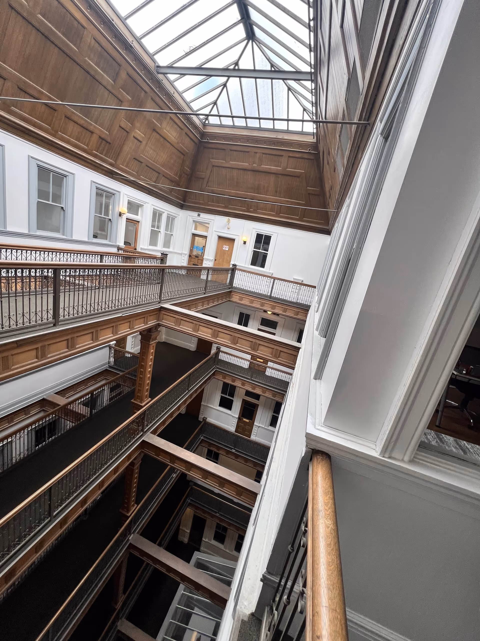 Interior multi-story atrium with wood paneling, railings, and a glass skylight.