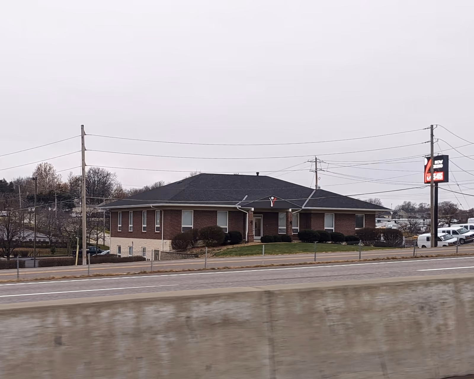 Exterior view of a single-story brick senior living facility along a road