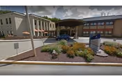 Exterior view of Wexford Healthcare Center with entrance canopies, landscaping, and a parked car.