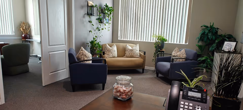 Interior lounge area with blue chairs, beige sofa, and plants.
