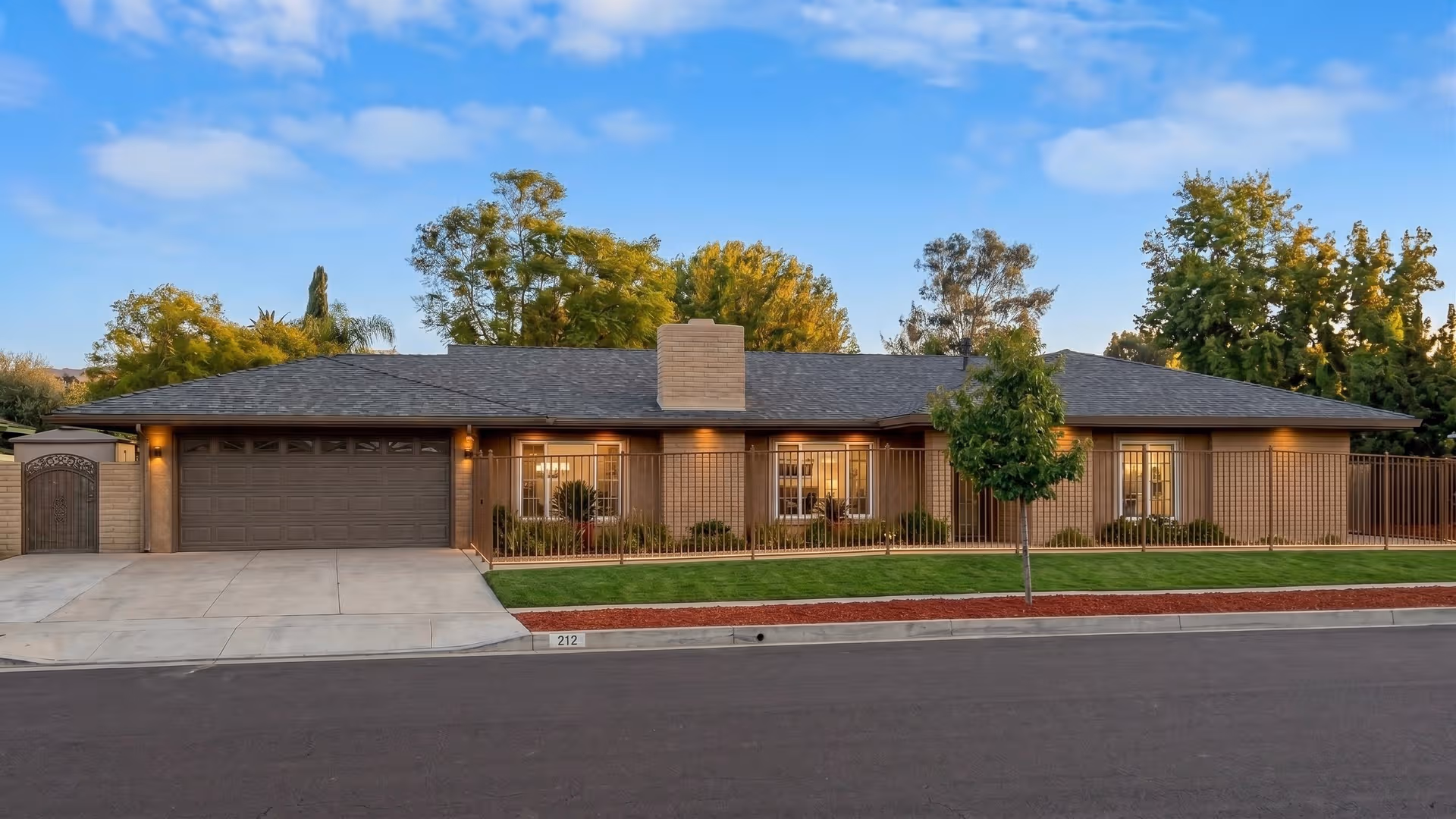 Single-story brick senior living facility exterior with a manicured lawn and gated front yard.