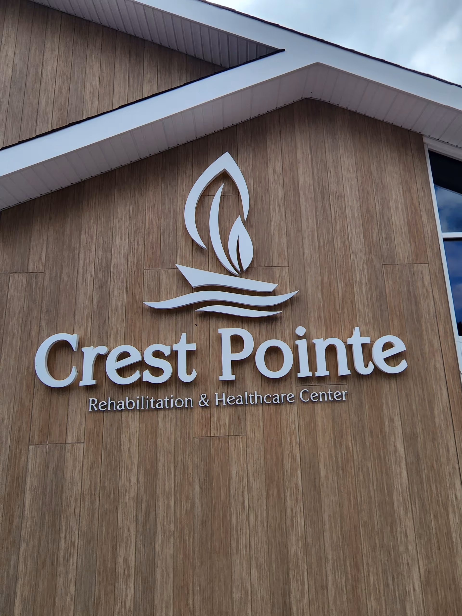 Exterior view of Crest Pointe Rehabilitation and Healthcare Center sign on a wooden facade