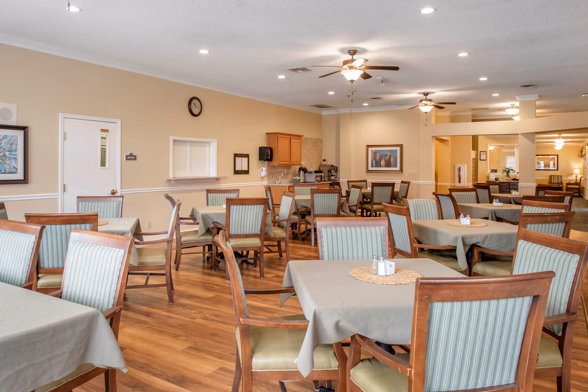 A spacious dining room with multiple tables, chairs, and a small serving counter.