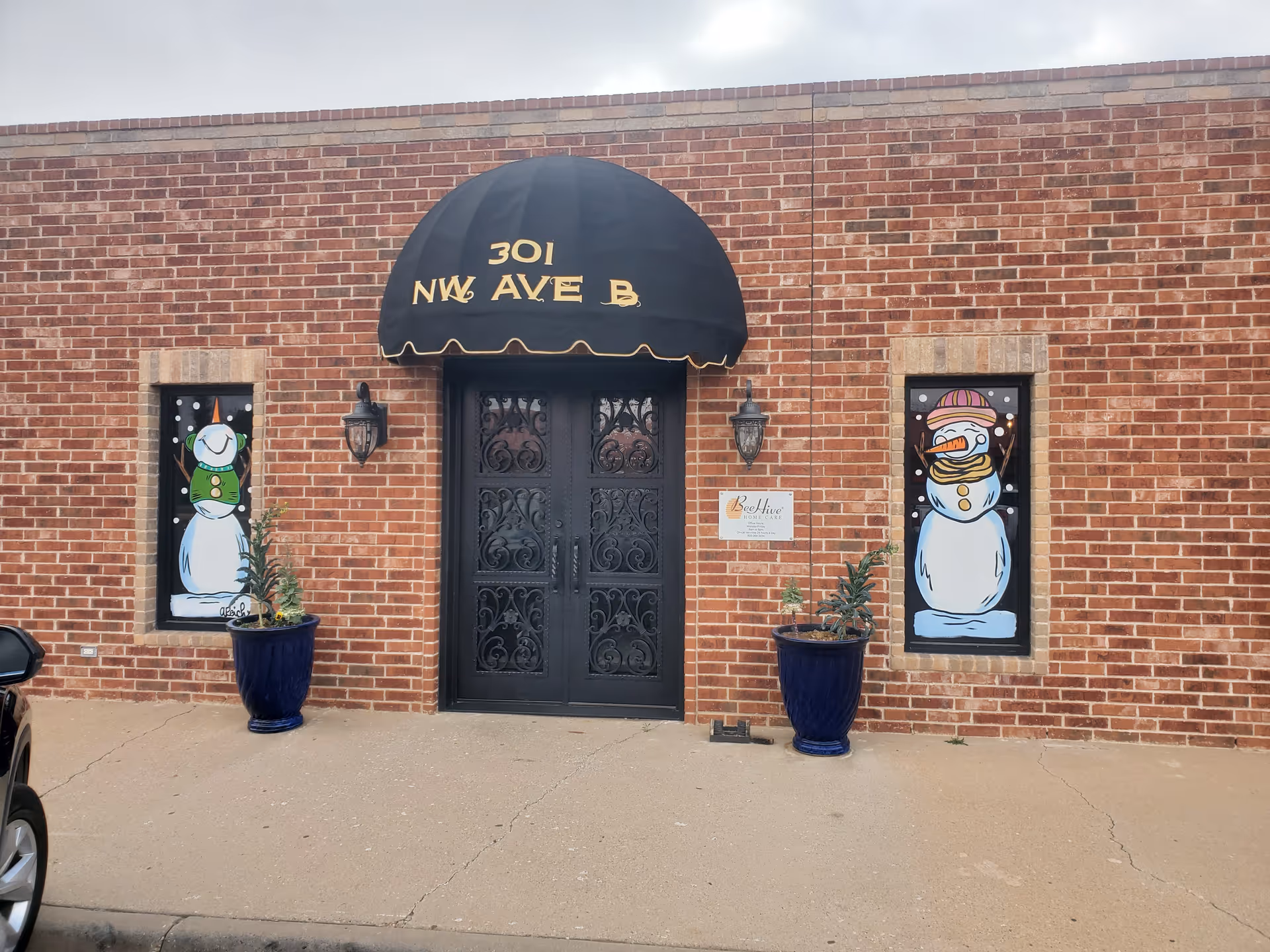 Brick building facade with ornate black doors, curved awning, and Beehive sign.
