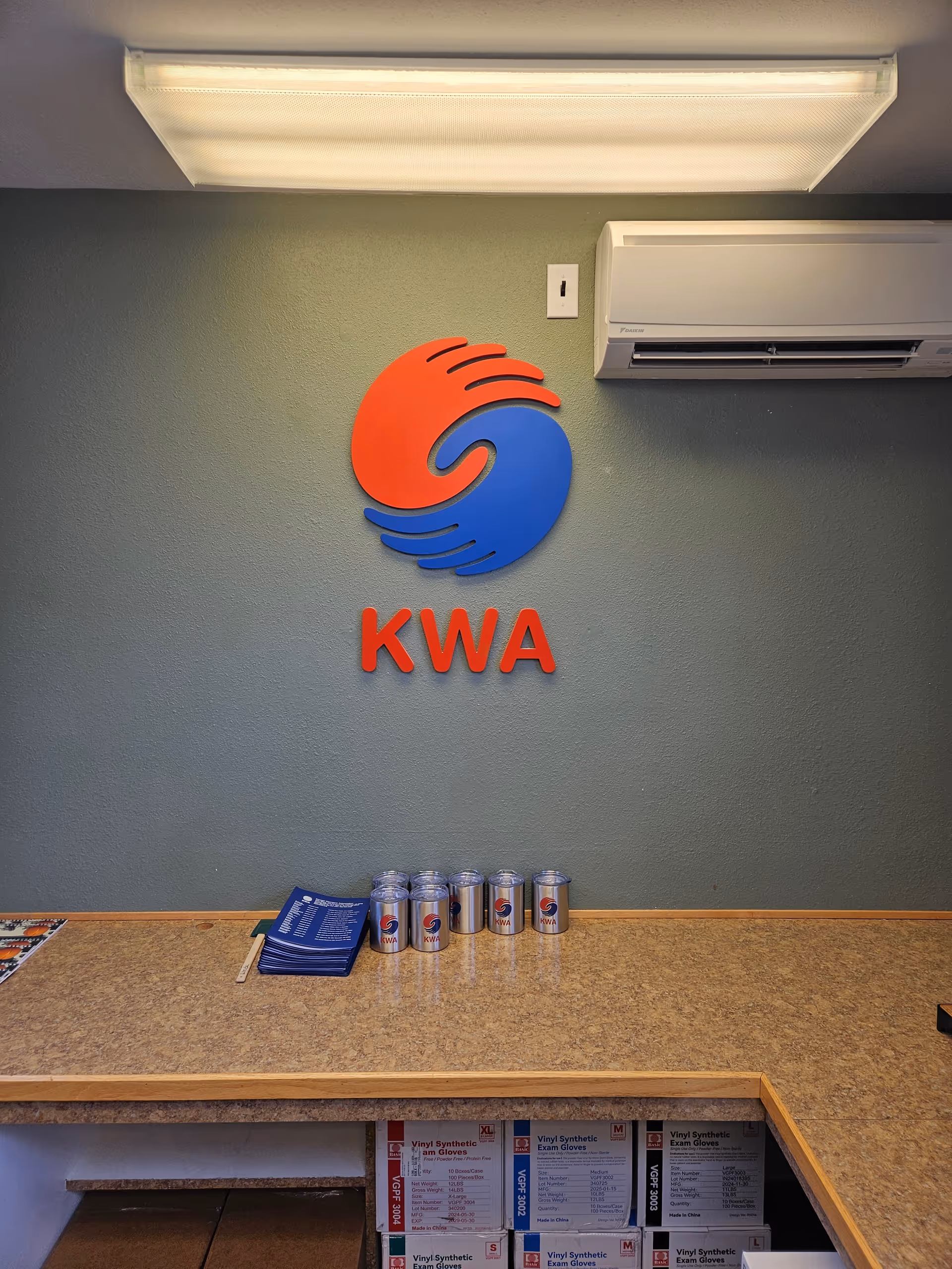 Reception counter with KWA logo on wall and blue and red branding.
