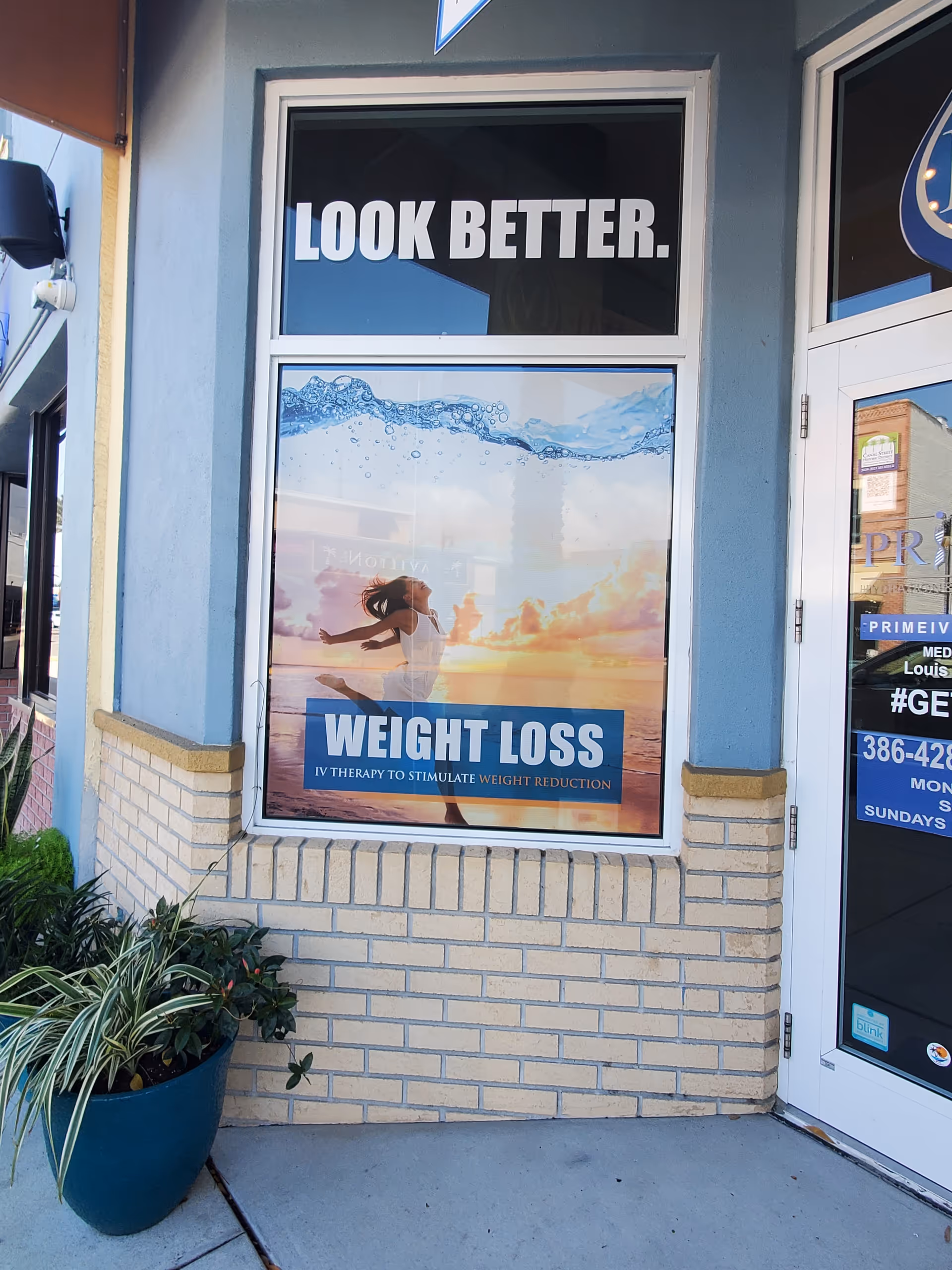 Storefront window displaying weight loss advertisement with plants outside.