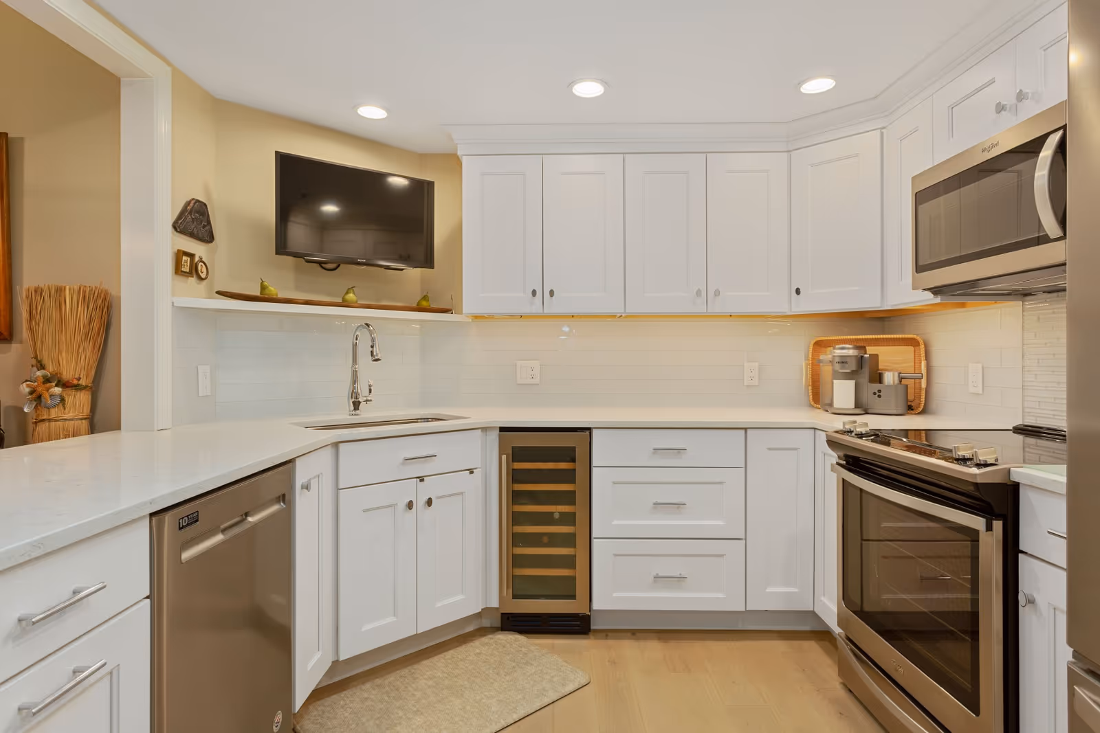Bright white kitchen with cabinets, stainless appliances, sink, and a wine cooler.