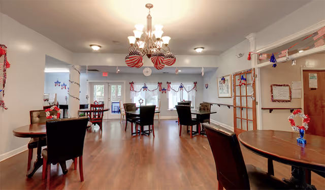 Spacious dining room with round tables, chairs, and festive holiday garlands.