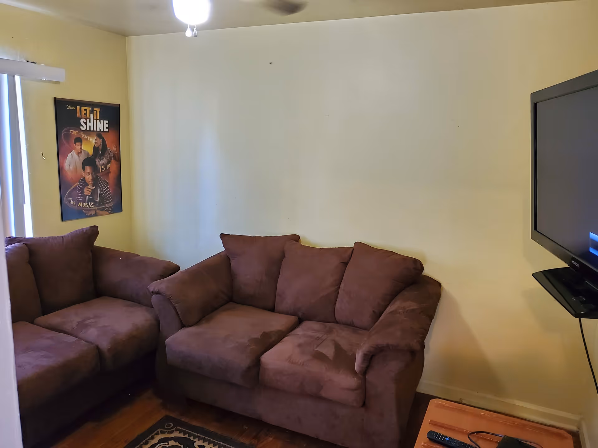 Purple sectional sofa beside a wall with a poster and mounted TV.