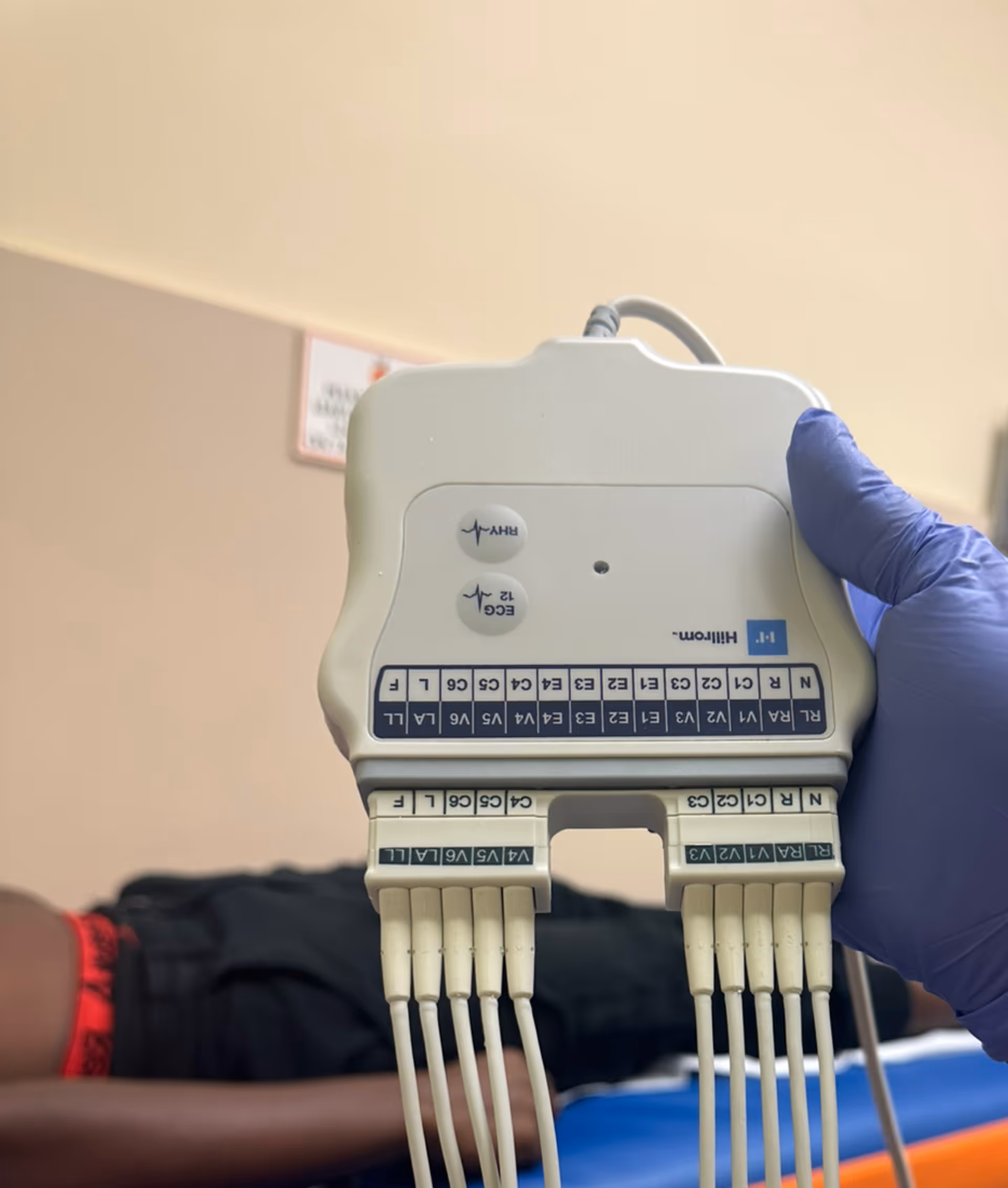 Close up of a medical device held by a gloved hand near a patient in bed.
