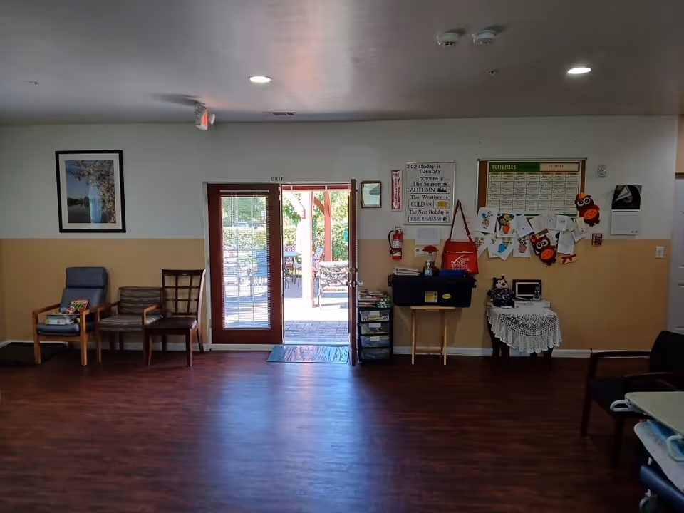 Lounge area of a retirement home interior with chairs, bulletin board, and glass exit door.