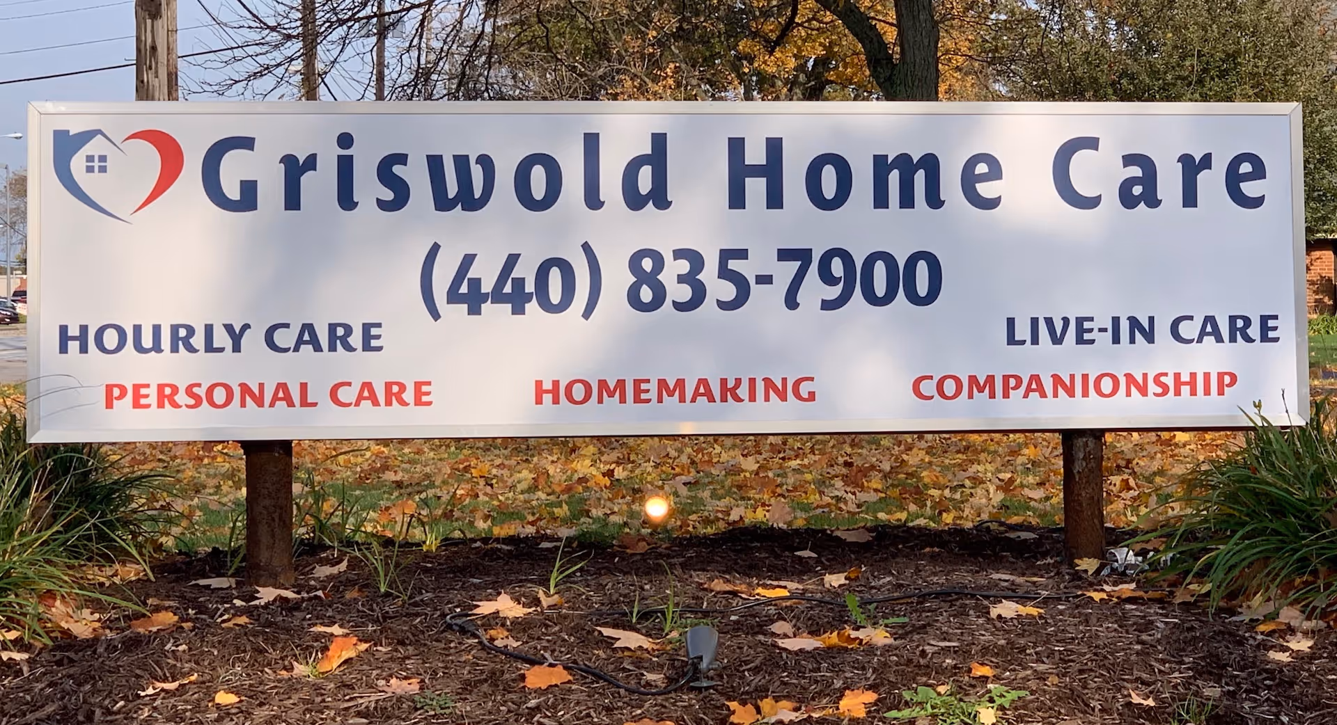 Large outdoor Griswold Home Care sign with phone number and service listings.