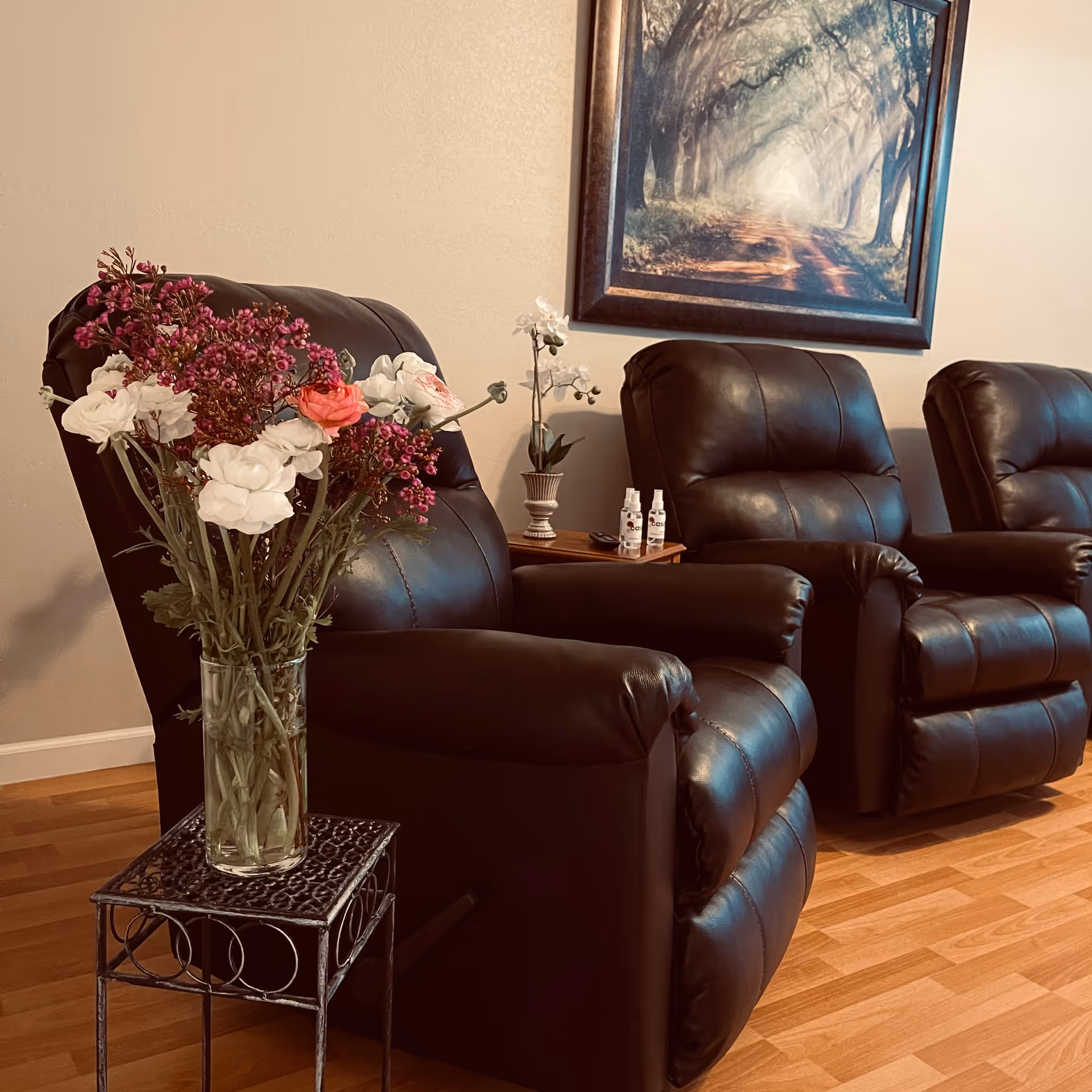 Leather recliners arranged in a living room with flowers and wall art.