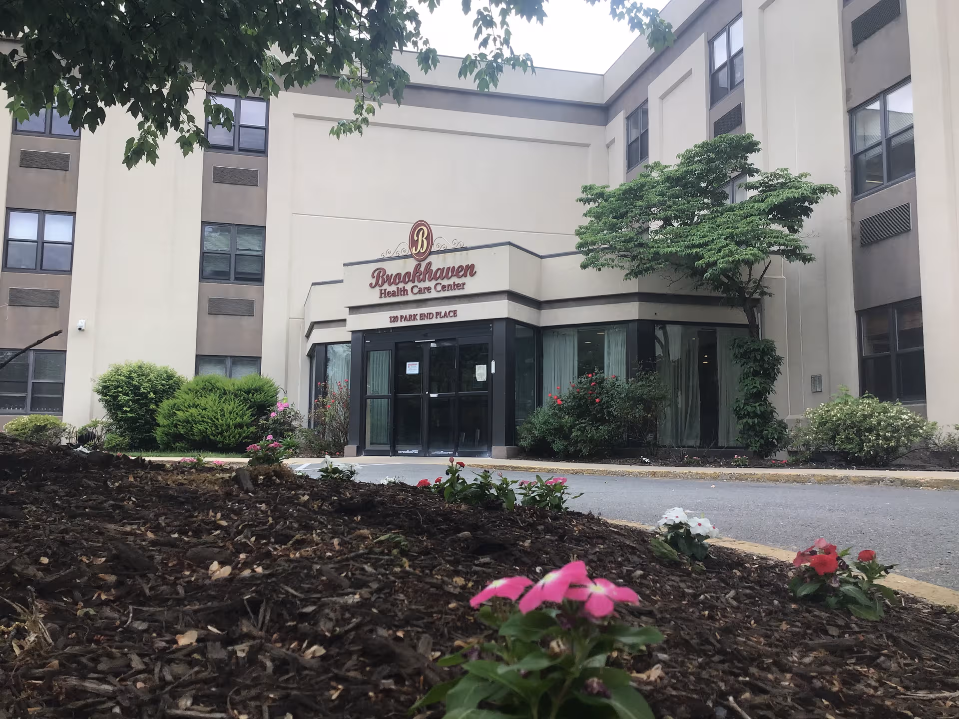 Front view of Brookhaven Health Care Center entrance with landscaping and trees.