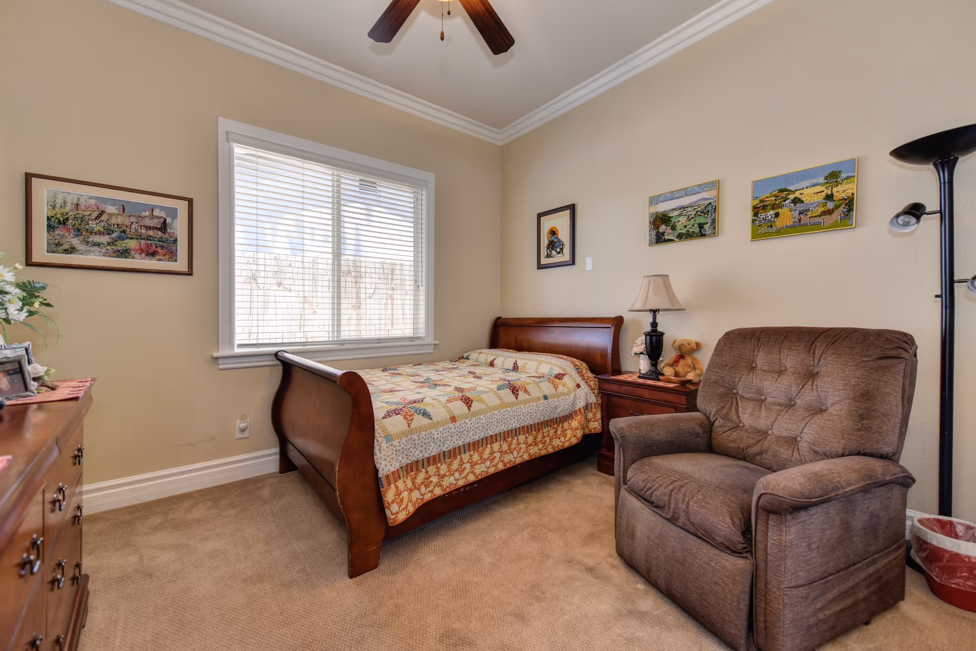 A cozy bedroom with a bed, armchair, dresser, and window at Splendor Oaks Senior Living #1.