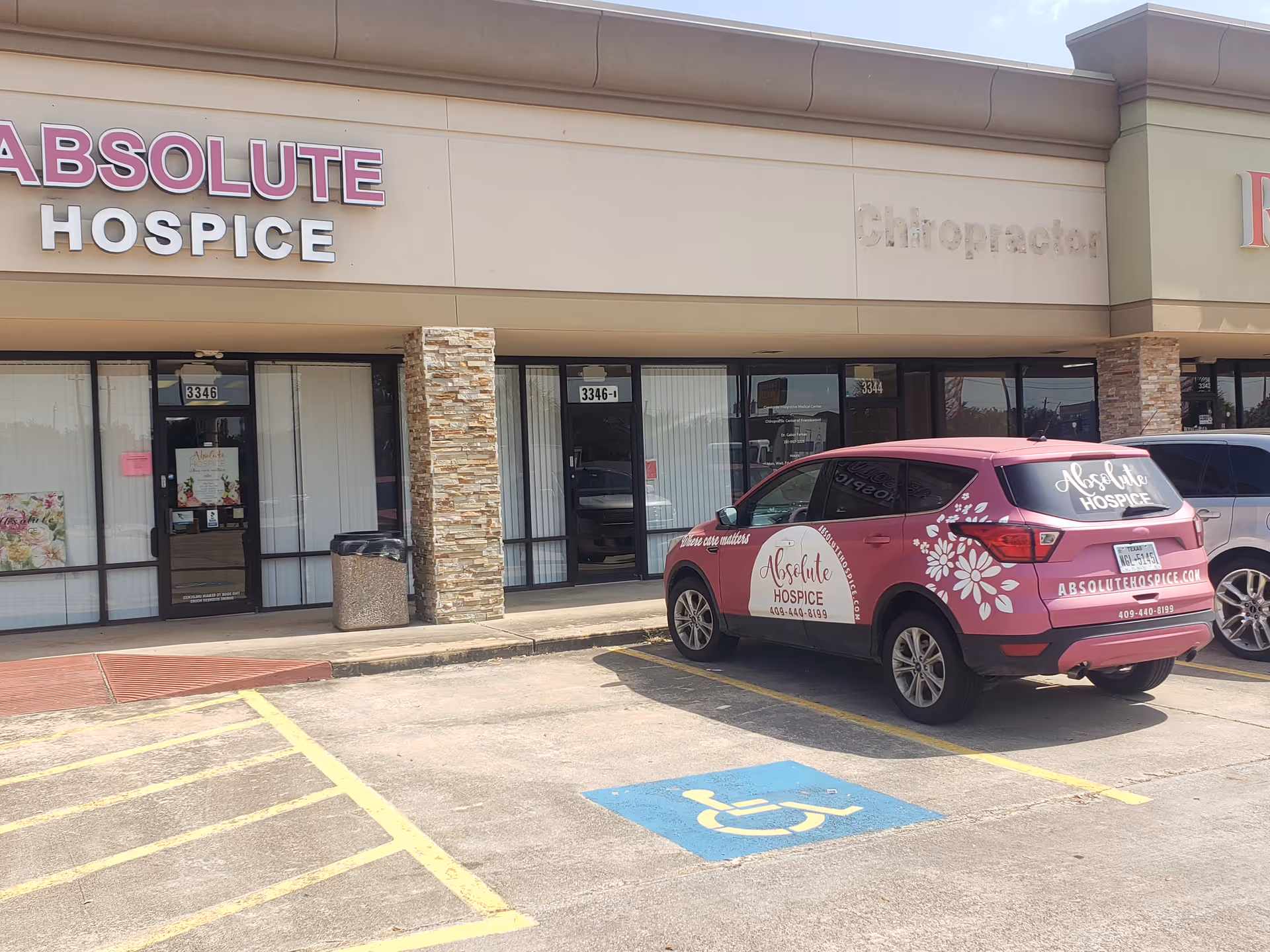 Exterior storefront of Absolute Hospice with a pink hospice vehicle parked outside.