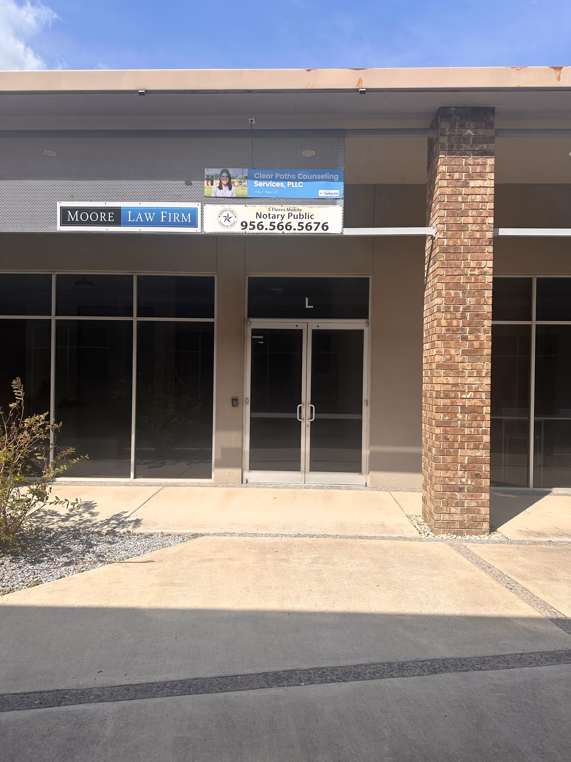 Exterior storefront with glass doors and multiple business signs, including Moore Law Firm.