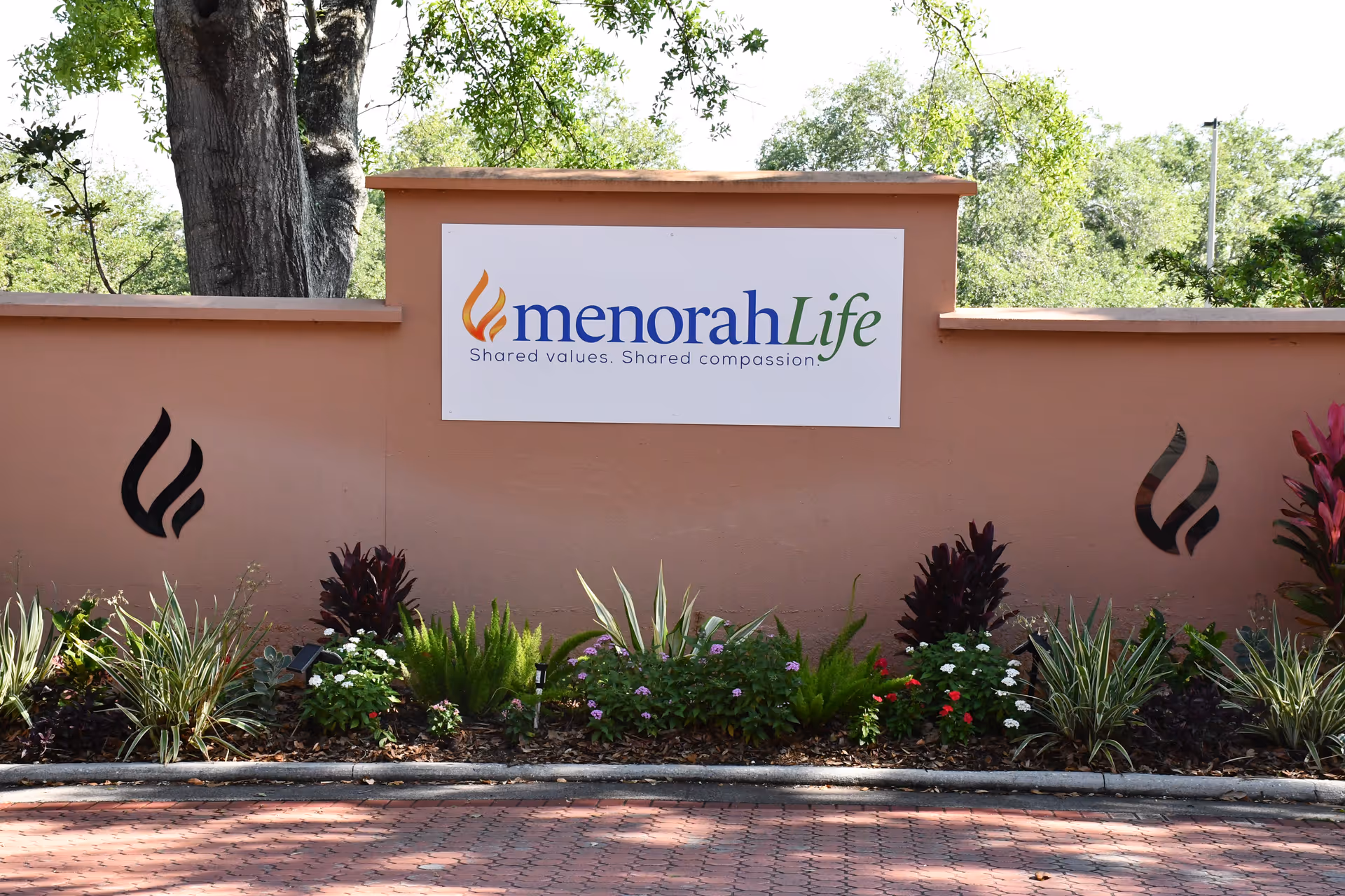 Exterior peach wall with Menorah Life sign and landscaped garden.