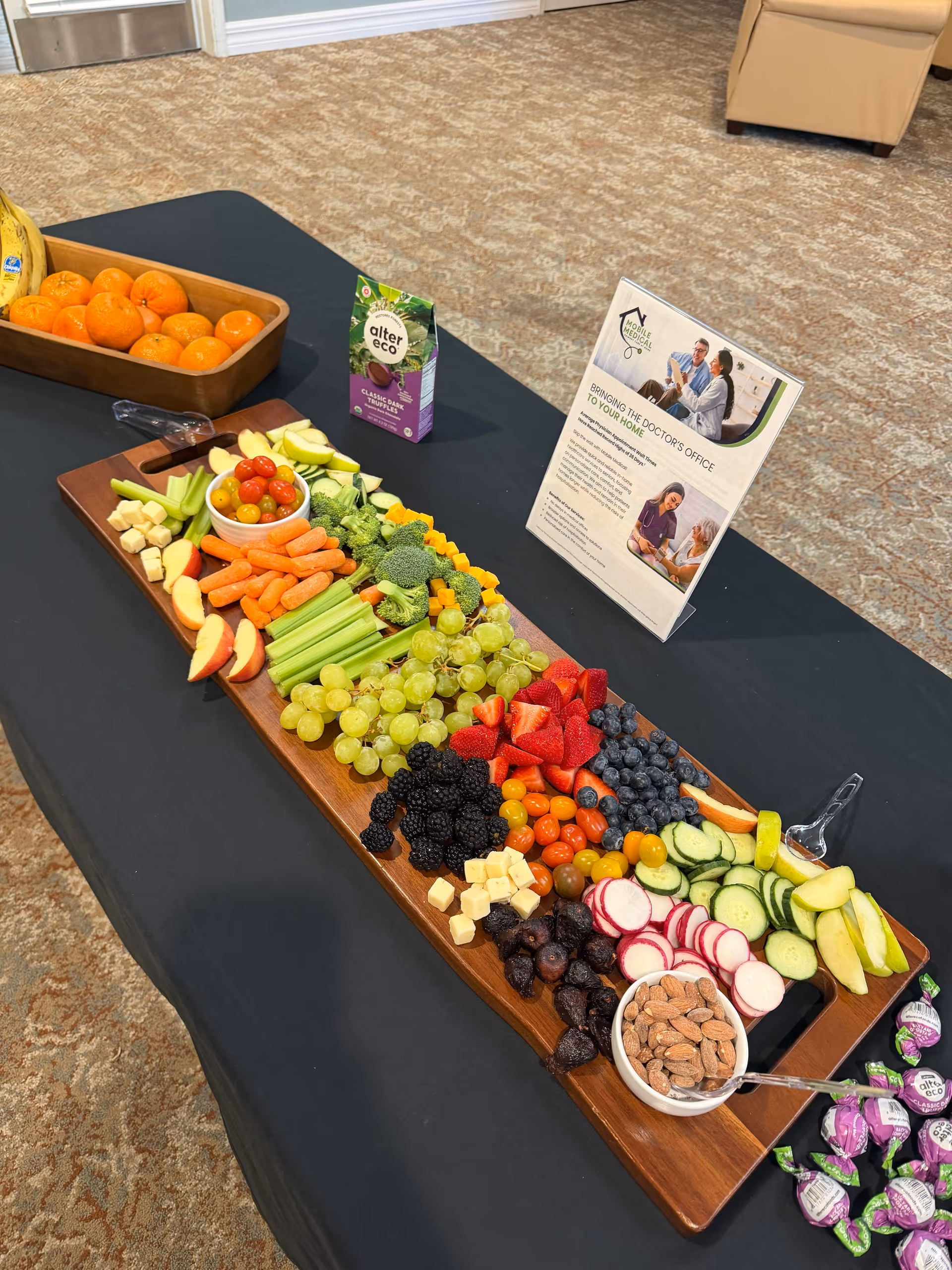 Indoor dining table with a long fruit and vegetable platter and promotional flyers.