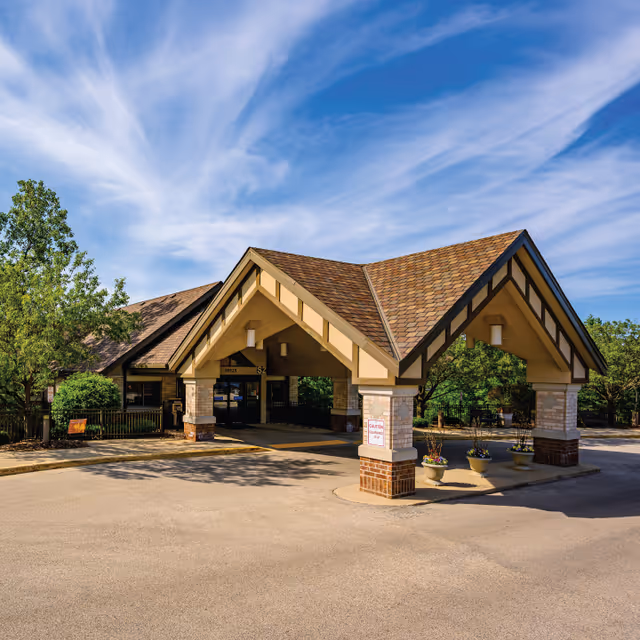 Entrance of Ascension Living Franciscan Place with a covered drop-off area and trees