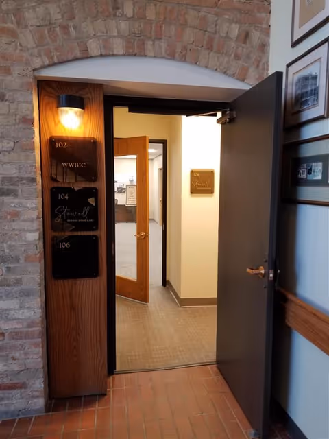 Interior hallway of a senior living facility with numbered doors and brick arch.