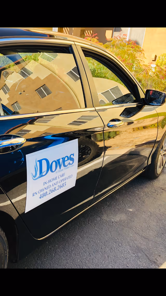 Black car with Dove's Home Care sign parked outside in sunlight