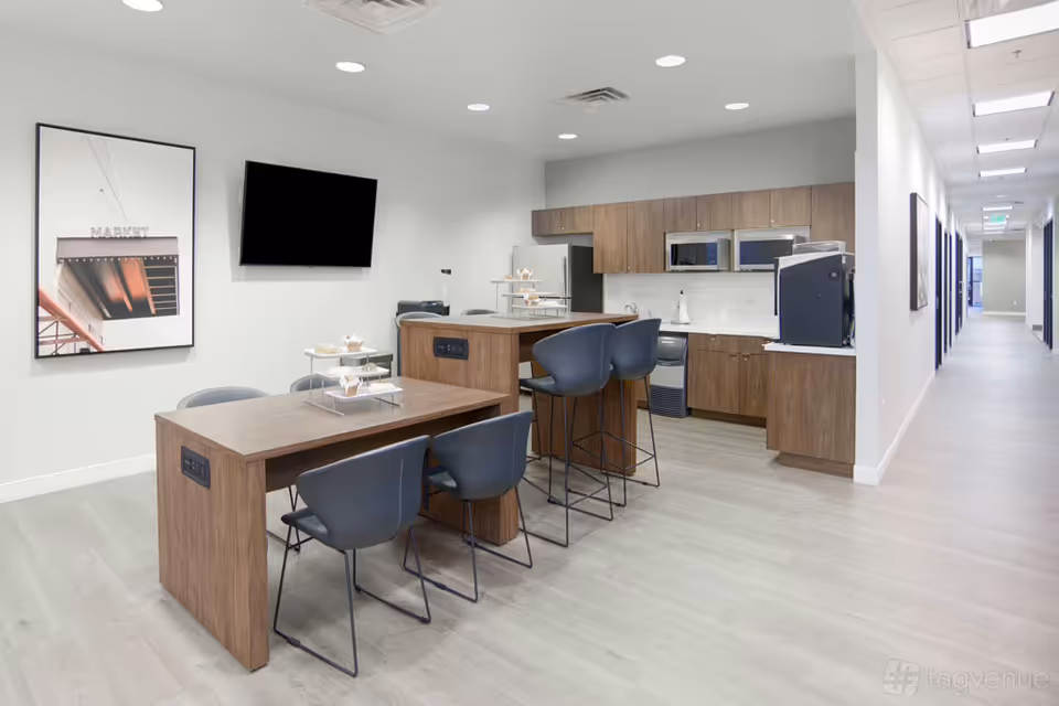 Modern facility kitchenette and dining area with bar stools and a long hallway.
