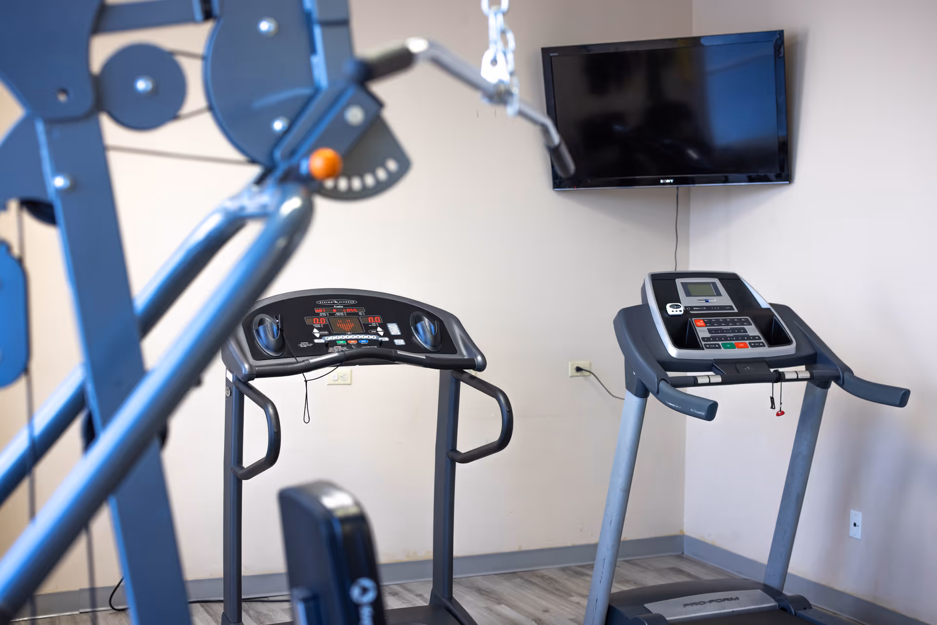 Interior gym with treadmills and a wall-mounted TV in a rehab center.