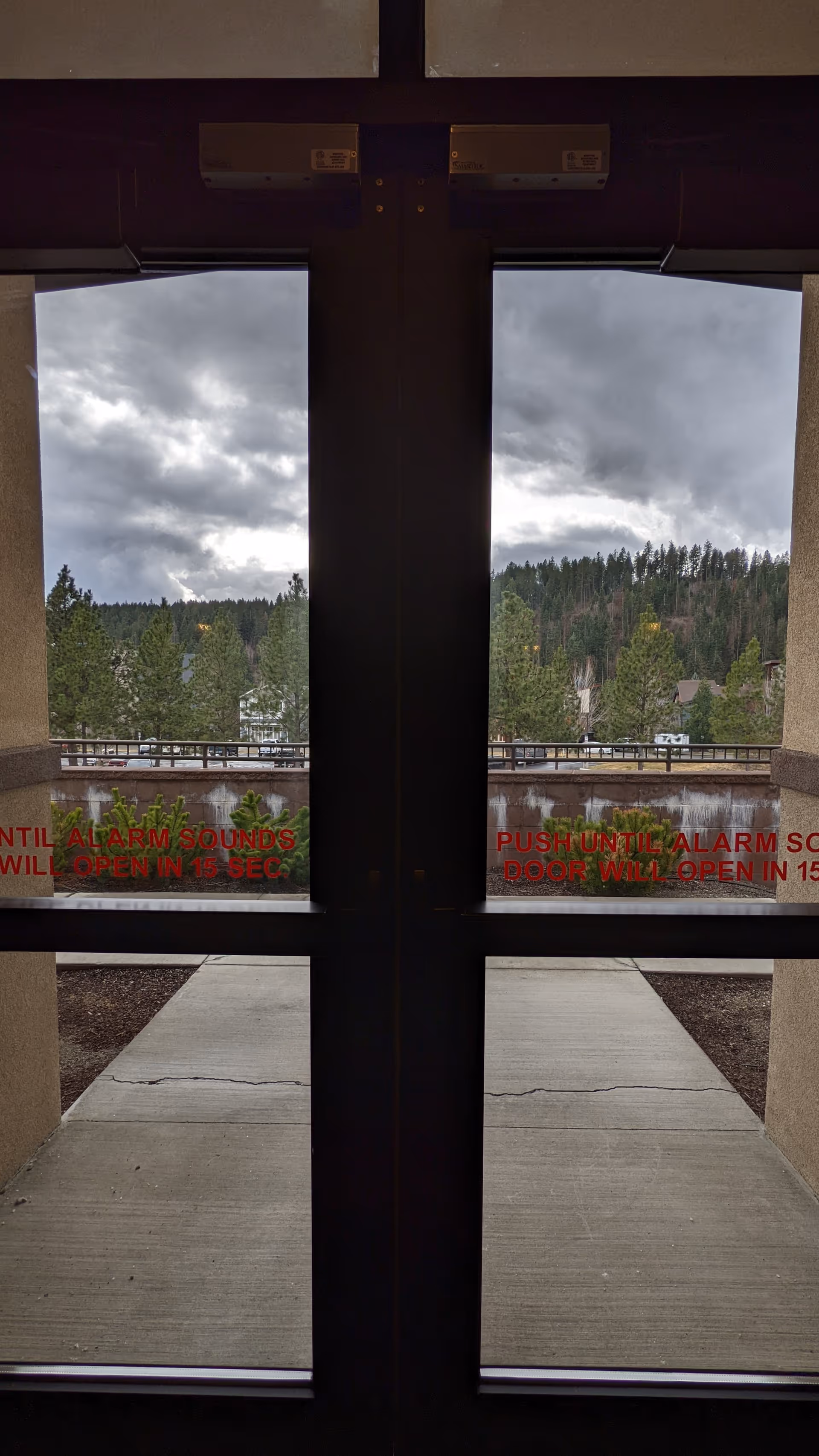 Two glass doors with red safety text, view of trees outside