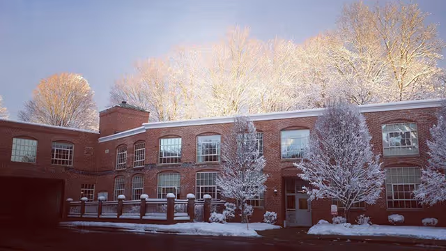 Snow-covered brick building with frosted trees in front of a senior living facility.