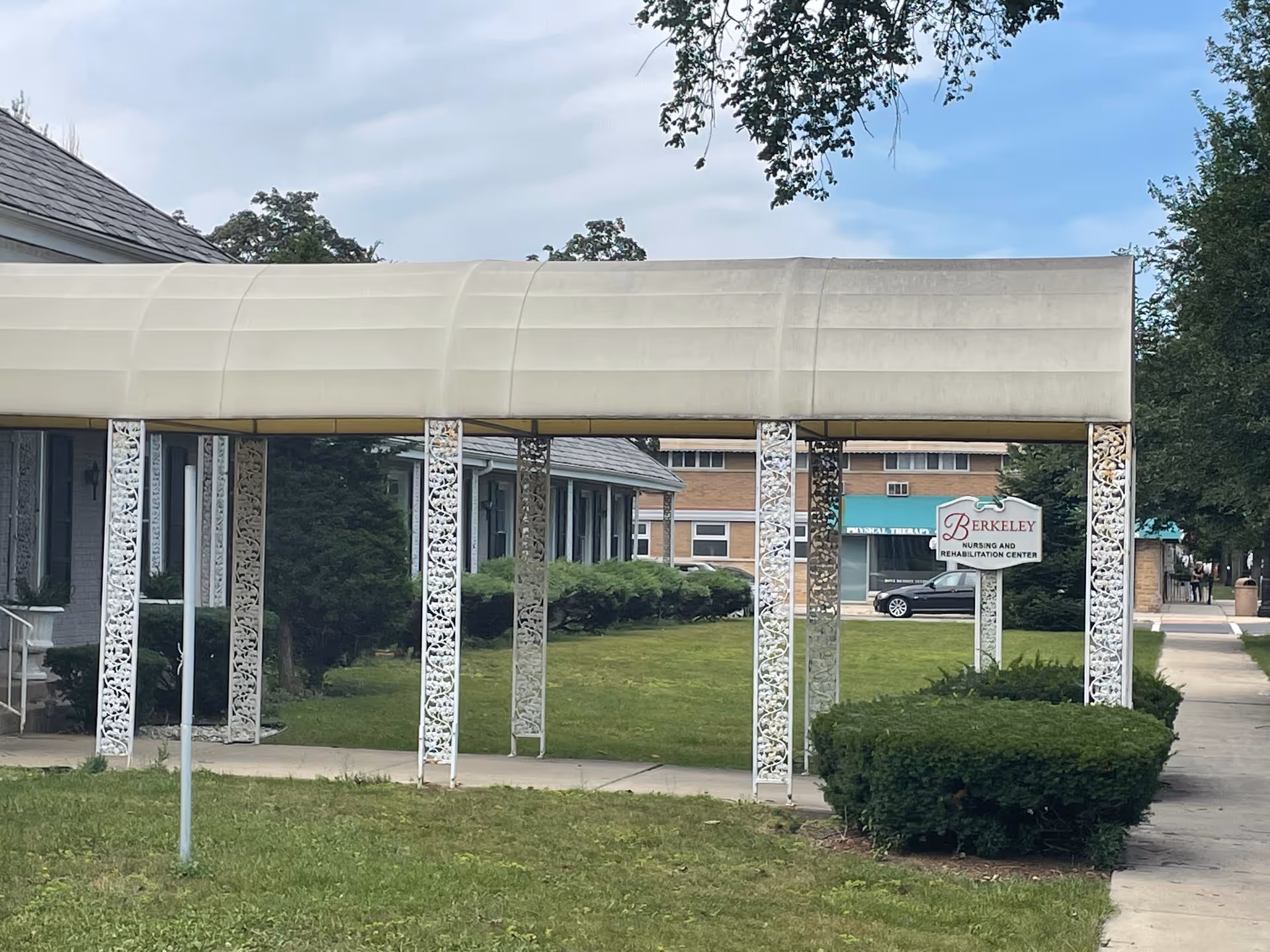 Exterior view of Berkeley Nursing & Rehabilitation Center with a covered walkway and sign.